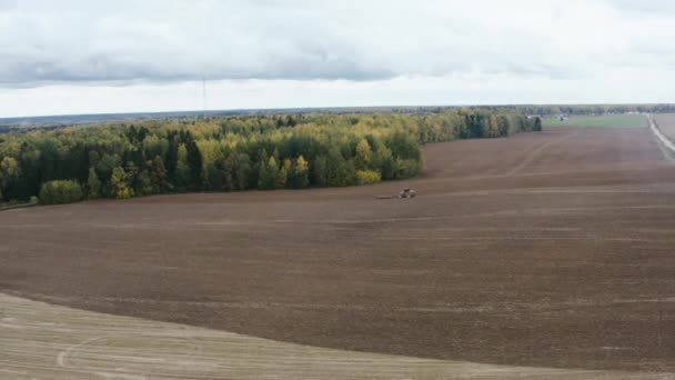 Aerial drone shot of tractor cultivating field in country during autumn. Farmer working day — Wideo stockowe