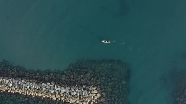 Man floating on sup. Aerial view of beautiful sea landscape. Drone shot of sea rocky stones. — Wideo stockowe