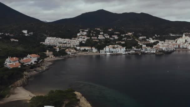 Aerial view of many yachts in beautiful bay of coastal resort town Cadaques on Cap de Creus peninsula. Drone shot of white houses in small seaside town surrounded with mountains, Spain — Stock Video