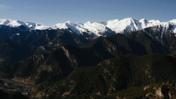 Drone shoot a breathtaking view of the snow-capped peaks of the mountains against a blue sky shot on a sunny day. — Stock Video