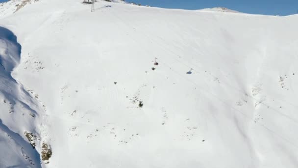 Drohnenblick Skilift. Skilift in luftiger Höhe transportiert Sportler zwischen schneebedecktem Berghang im Skigebiet. — Stockvideo