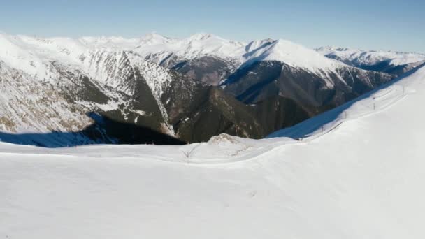 Höga berg med snöiga toppar och skidlift för transport på vinterort. Flyglandskap vinter berg och hiss för skidåkare och snowboardåkare. — Stockvideo