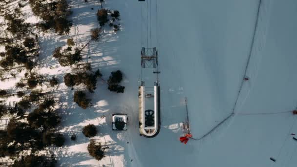 Skilift op wintersportplaats in besneeuwde berg voor transportskiërs en snowboarders vanuit de lucht. Top uitzicht van vliegende drone skilift werken op de winter sneeuw piste. — Stockvideo
