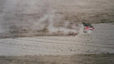 Bir traktörün tırmığı tarladaki toprağı işliyor..
