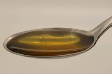 Kaşığın üzerindeki bal beyaz arka planda izole edilmiş. Soğuk algınlığı için doğal ilaçlar..