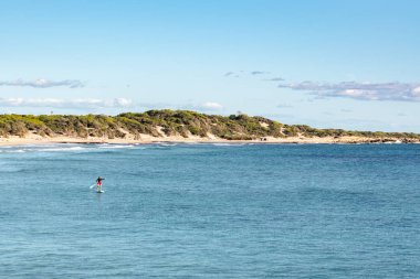 Ibiza ve Formentera 'daki Salinas Ulusal Parkı' ndaki ses salinalarının ıssız sahillerinde sörf yapan bir adam..