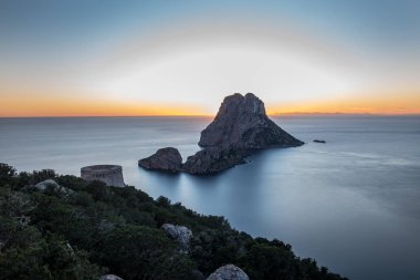 Güneşin Es Vedra 'da Torre del Savinar ile birlikte batışının göz kamaştırıcı manzarası Es Vedra, Sant Josep de Sa Talaia, İbiza, İspanya.