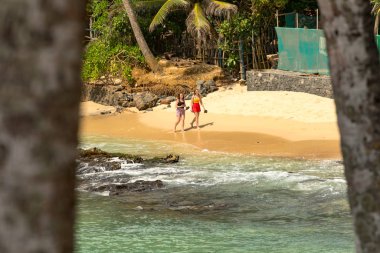 Mirissa, Sri Lanka: 2019 20 Nov: Batı Mirissa, Sri Lanka 'da Hindistan cevizi palmiyesi tepesinde bulutlu bir gün doğumu yaşayan insanlar