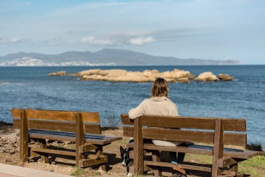 Sant Marti De Ampuries, Girona, İspanya: 2020 Şubat 2008: La Escala 'daki Platja de Les Muscleres' deki Genç Sarışın Kadın İşsizlik harabelerinin arkasında, Giron, Katalonya, İspanya.
