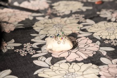 Genç tasarımcı atölyesinde renkli ve çiçekli kumaşlarla çalışıyor..