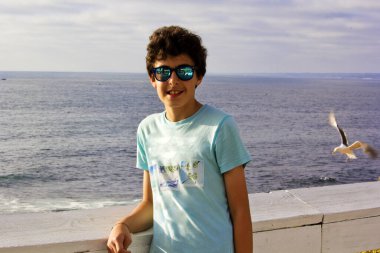 Yakışıklı çocuğun portresi San Diego La Jolla Plajı 'nda kameraya gülümsüyor.