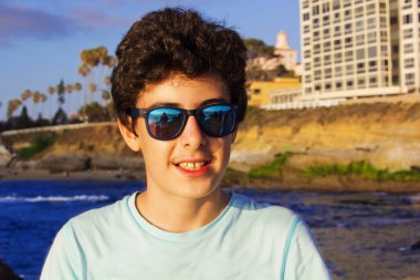 Yakışıklı çocuğun portresi San Diego La Jolla Plajı 'nda kameraya gülümsüyor.