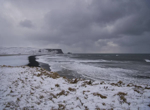 The snowy coast in Iceland with the black sand beach