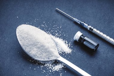 Minimalist düz kompozisyon şeker, kaşık, şırınga ve şişeler koyu arkaplanda. Tıbbi, Sağlık ve Diyabet Konsepti. Üst görünüm ve seçici odak.