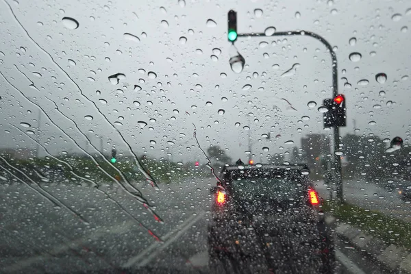 Rain drop falling on car windshield, drive car on street in city in heavy rain