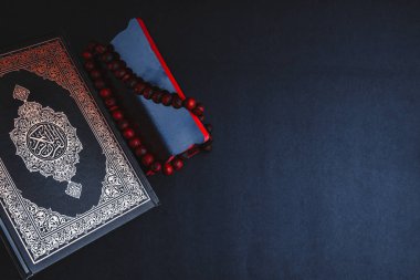 El-Kur 'an' ın Arapça el yazısı ve tasbih 'in ya da siyah arkaplanda tespih boncuğunun yazılı olduğu Kutsal Kur' an. Seçici odak ve kırpma parçası