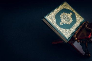 El-Kur 'an' ın Arapça el yazısı ve tasbih 'in ya da siyah arkaplanda tespih boncuğunun yazılı olduğu Kutsal Kur' an. Seçici odak ve kırpma parçası