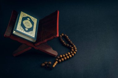 El-Kur 'an' ın Arapça el yazısı ve tasbih 'in ya da siyah arkaplanda tespih boncuğunun yazılı olduğu Kutsal Kur' an. Seçici odak ve kırpma parçası