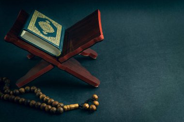 El-Kur 'an' ın Arapça el yazısı ve tasbih 'in ya da siyah arkaplanda tespih boncuğunun yazılı olduğu Kutsal Kur' an. Seçici odak ve kırpma parçası