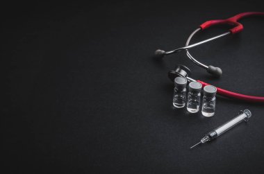 Stetoskop, şişeler ve siyah arka planda şırınga. Seçici odak ve kopyalama alanı