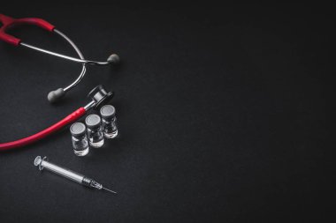 Stetoskop, şişeler ve siyah arka planda şırınga. Seçici odak ve kopyalama alanı