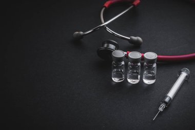 Stetoskop, şişeler ve siyah arka planda şırınga. Seçici odak ve kopyalama alanı