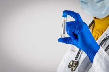 Stetoskop ve doktorun elleri beyaz arka planda numune şişesini tutuyor. Seçici odak ve kırpma parçası