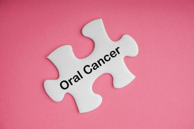 Pembe arka planda beyaz yapboz ile ORAL CANCER metin. Kanser Bilinci Kampanyası