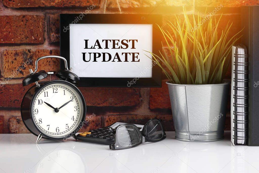 LATEST UPDATE text with alarm clock, books and vase on brick background. Business, Quotes and Copy Space concept