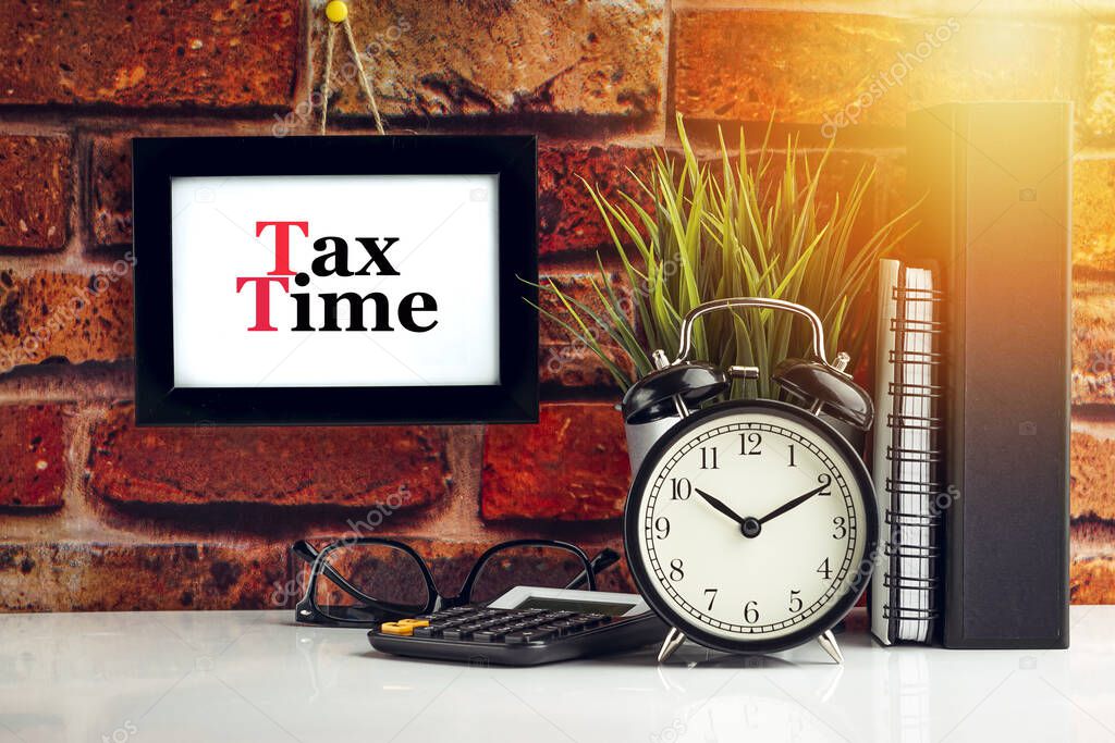 TAX TIME text with alarm clock, books and vase on brick background. Business, Quotes and Copy Space concept