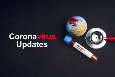 Coronavirus veya Covid-19 metni steteskop, dünya küresi ve kan örneği vakum tüpüyle siyah arka planda günceller. Covid veya Coronavirus Kavramı 