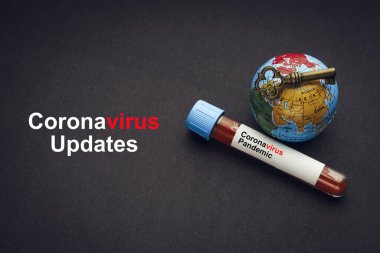 CORONAVIRUS UPDATES metni anahtar, dünya küresi ve kan örneği vakum tüpü siyah zemin üzerinde. Covid-19 veya Coronavirus Kavramı 
