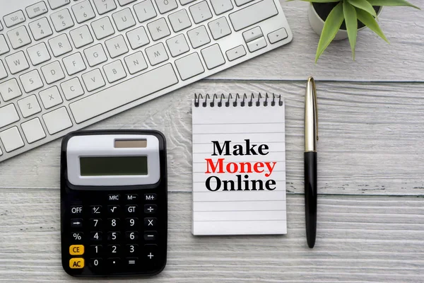 MAKE MONEY ONLINE text with notepad, keyboard, decorative vase, fountain pen, and calculator on wooden background. Business and copy space concept