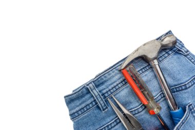 Beyaz arka planda kot pantolon, tornavida, çekiç ve kerpeten. Kot pantolon desenli, aletli mavi kot pantolon. Boşluk konseptini kopyala