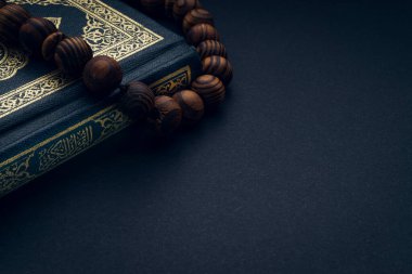 Al-Kur 'an' ın Arapça el yazısı ve siyah arkaplanda tespih ya da tasbih anlamına gelen kutsal Kur 'an. Boşluk ve kırpma parçalarını kopyala