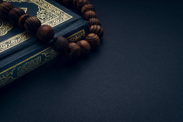 Священный Аль-Коран с письменной арабской каллиграфией смысл Аль-Корана и четки или tasbih на черном фоне. Копирование пространства и фрагмента урожая
