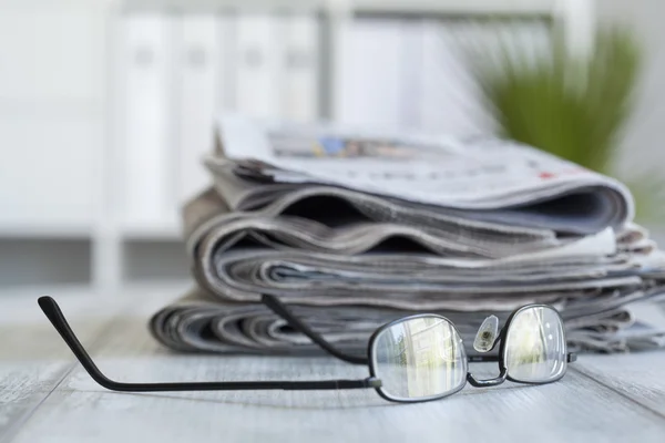 Pilha de jornais e óculos — Fotografia de Stock