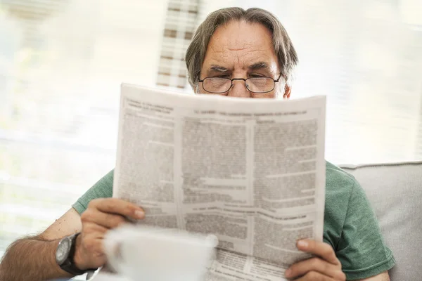 Senior mand læser avis derhjemme - Stock-foto