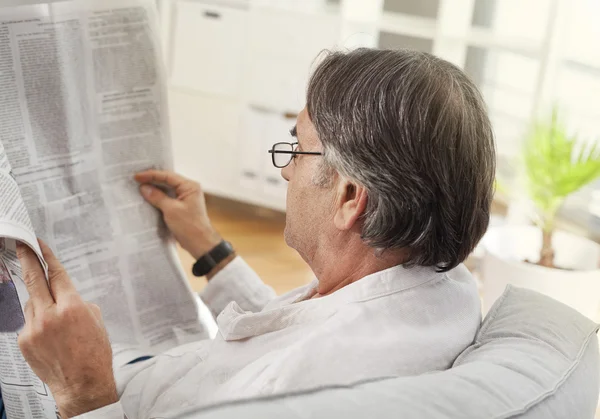 Hombre mayor leyendo el periódico en casa — Foto de Stock