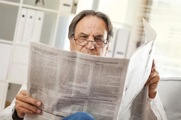 Senior man reading newspaper at home — Stock Photo, Image