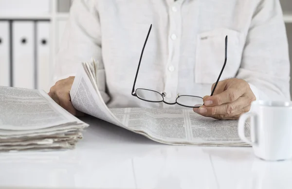 Hombre leyendo periódico y sosteniendo anteojos —  Fotos de Stock