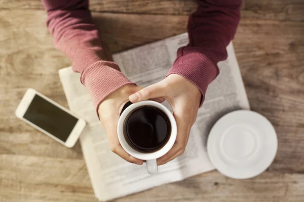 Mujer joven leyendo periódico y sosteniendo café — Foto de Stock