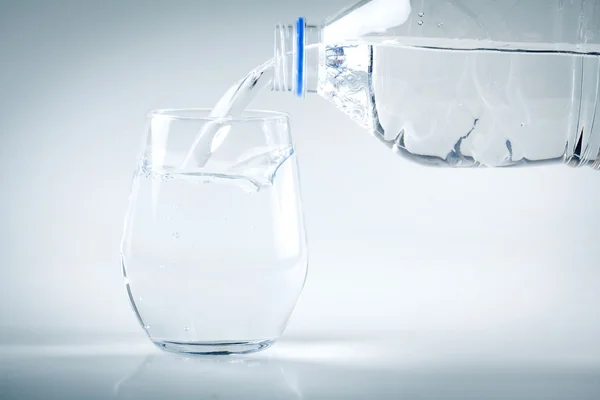 Tekoucí voda na sklo na bílém pozadí — Stock fotografie