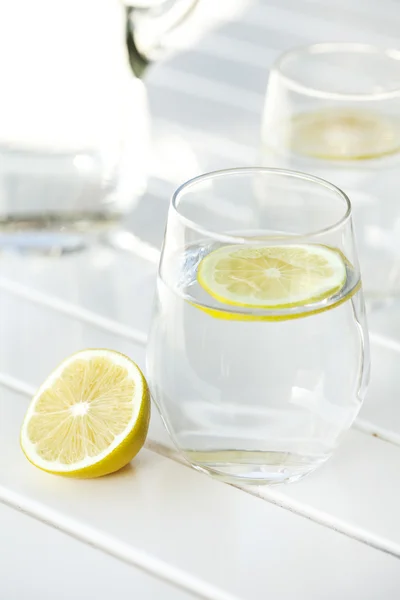 Copo de água com limão sobre fundo branco — Fotografia de Stock