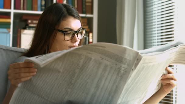 Молодая женщина читает газету — стоковое видео
