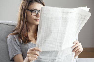 Genç kadın gazete okuyor.