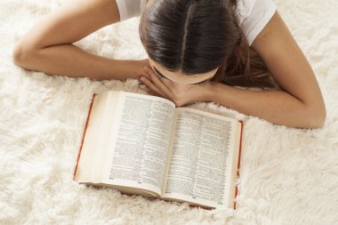 Genç kadın halı üzerinde kitap okuma