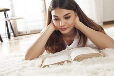 Genç kadın halı üzerinde kitap okuma