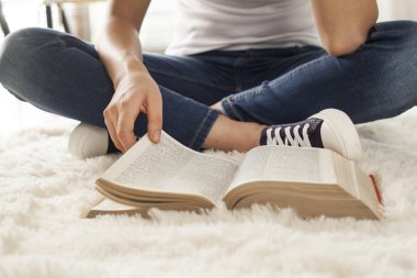 Genç kadın halı üzerinde kitap okuma