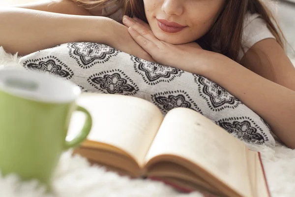 Mladá žena čte knihu na koberci — Stock fotografie